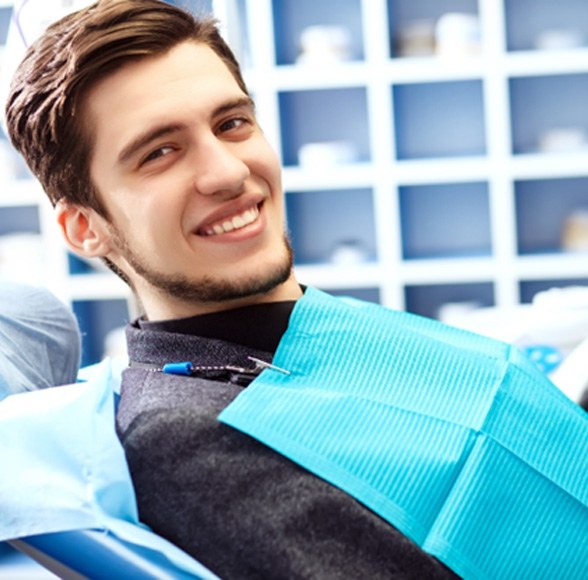 Man leaning back in a dental chair and smiling