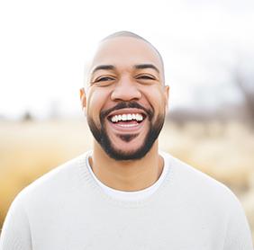 Man in white shirt smiling outside
