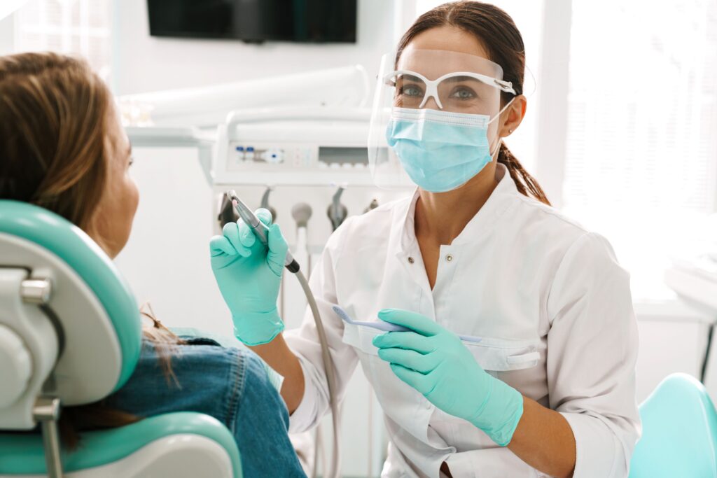 Dentist in protective gear approaching patient for treatment