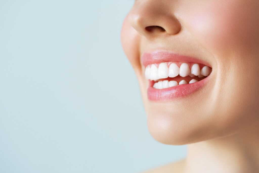 Nose-to-chin 3/4 profile view of woman smiling with gray background